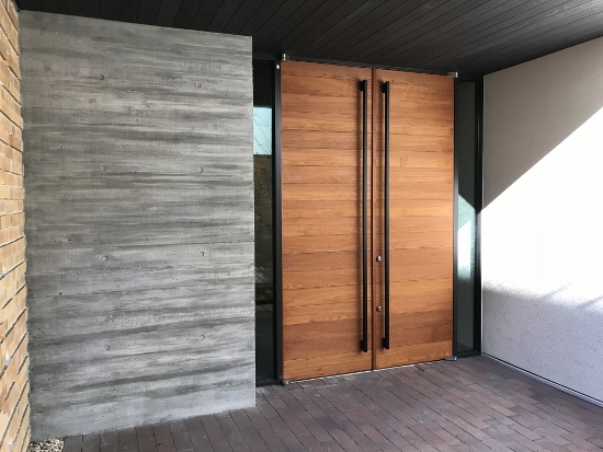 両開きの玄関扉と杉板型枠で造られたコンクリート打ちっぱなしの壁